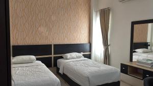 a hotel room with two beds and a mirror at Hotel Khariz in Bukittinggi