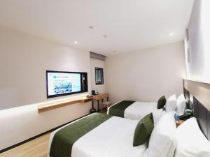 a hotel room with two beds and a flat screen tv at Green Tree Inn Express Shanghai Bund Yuyuan Xiaonanmen Metro Station in Shanghai