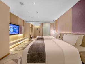 a large bedroom with two beds and a flat screen tv at Lavande Hotel Wuhan Jianghan Road Dunli Gate Metro Station in Wuhan