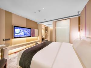 a bedroom with a large bed and a flat screen tv at Lavande Hotel Wuhan Jianghan Road Dunli Gate Metro Station in Wuhan