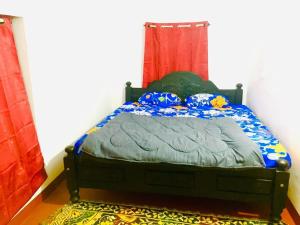 a bed in a bedroom with a red curtain at Vintage Breeze Home Stay in Madikeri