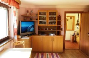 a living room with a television and a cabinet with wine glasses at Haus Reinstadler in Imst