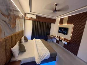 a hotel room with a bed and a flat screen tv at Aura Stays in Lucknow