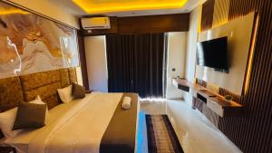 a hotel room with a bed and a flat screen tv at Aura Stays in Lucknow