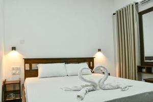 a bedroom with a bed with towel swans on it at Coconut Resort Arugambay in Arugam Bay