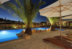 ein Swimmingpool mit zwei Stühlen und einem Sonnenschirm in der Unterkunft Luxury Getaway for 2 Jacuzzi Studio at Villa Lojena ID111-7 in Murter