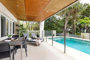 een patio met een tafel en stoelen naast een zwembad bij Prime Location, Views & Sunsets, Walk to Hastings in Noosa Heads