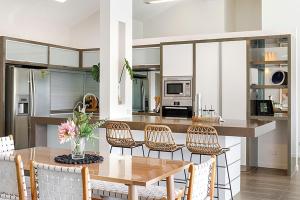 een keuken met een tafel en stoelen en een keuken met een aanrecht bij Prime Location, Views & Sunsets, Walk to Hastings in Noosa Heads +22 foto's