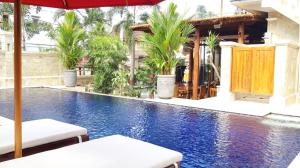 a swimming pool with two chairs and an umbrella at Grand Raka Homestay in Lovina