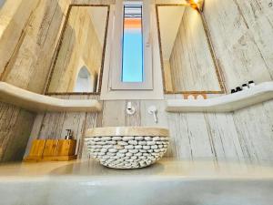 Utopia boutique villa on-in the water between 2 seas ideal 5 people في Kástron: حمام مع حوض حجري كبير ومرايا