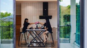 two women are sitting at a table in a house at Private Sanctuary Yanui beach in Nai Harn Beach
