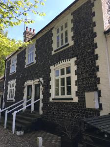 a stone house with white windows and stairs on it at The Crown Hotel in Mundford