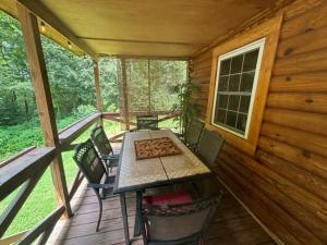 a table and chairs on the porch of a cabin at Creekside with views - jacuzzi firepit arcade in Cosby