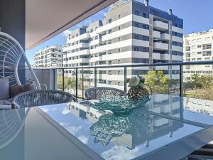 a glass table with chairs on a balcony with a building at Hanami Luxury Apartment Connecta in Estepona