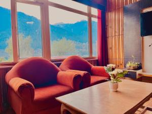 una stanza con due sedie e un tavolo e finestre di The Town House - Lavish & Luxury Rooms Near mall Road Manali a Manāli