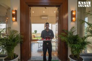a man holding a tray of food in a hallway at StayVista at Echoes of Ease with Bonfire & WiFi in Rishīkesh