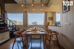 a dining room with a wooden table and chairs at StayVista at Echoes of Ease with Bonfire & WiFi in Rishīkesh