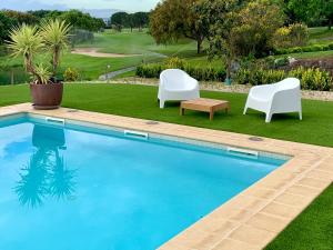 a swimming pool with two white chairs and a table at Villa de Lujo en Campo de Golf - Costa Brava in Peralada