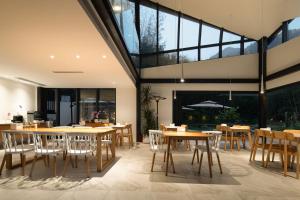 a restaurant with wooden tables and chairs and large windows at Congxi Creek Resort in Conghua