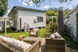 a backyard with wicker furniture and an umbrella at Kombi Cottage Fully accessible in Tairua