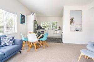 a living room with a blue couch and chairs at Kombi Cottage Fully accessible in Tairua