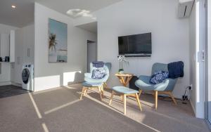 a living room with two chairs and a table at Kombi Cottage Fully accessible in Tairua