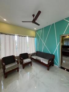 a living room with two chairs and a ceiling fan at Rest & Relax Resort in Yelagiri