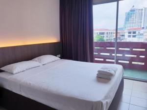 a bedroom with a white bed with a large window at Champcity Hotel Sdn Bhd in Kuantan