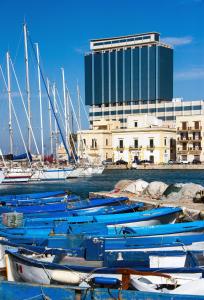 un gruppo di barche ormeggiate in un porto con un edificio di Hotel Bellavista Club-Caroli Hotels a Gallipoli