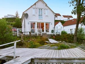 una casa bianca con un molo di legno di fronte di 9 person holiday home in GURSKØY-By Traum a Kjellsund