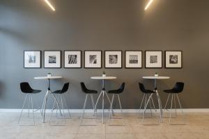 a group of tables and chairs against a wall with pictures at INNSiDE by Meliá Wolfsburg in Wolfsburg +58 photos