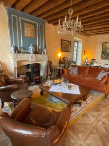 a living room with leather furniture and a fireplace at Le Presbytere de Leyrat in Leyrat