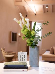 een blauwe vaas met witte bloemen op een tafel bij PALAZZO CIOPETA - Italian Excellence in Verona