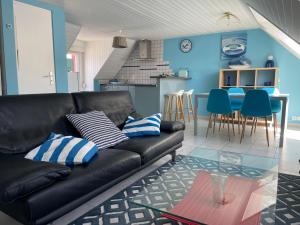 a living room with a black leather couch and blue walls at Le Bleu, T2 proche plage de Morgat in Crozon