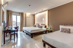 Una habitación de hotel con dos camas y un escritorio. en La Griffe Hotel Roma, en Roma