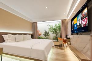 a bedroom with a large bed and a flat screen tv at Meiyi Grand Hotel Shenzhen Convention & Exhibition Center Huanggangcun Metro Station Branch in Shenzhen