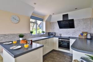 une cuisine avec des armoires blanches et un comptoir noir dans l'établissement Beer View Cottage, à Beer