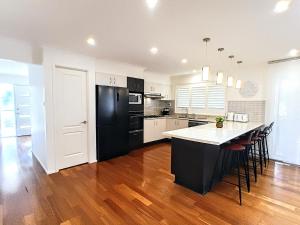 a kitchen with black appliances and a wooden floor at Shell Cove,Game Room, 3 Baths, King Bed, 7kW EV Point, Spacious 1-Story Home in Dunmore