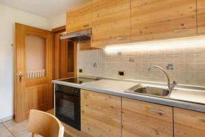 a kitchen with wooden cabinets and a sink at Baita Lorella in Livigno +152 photos