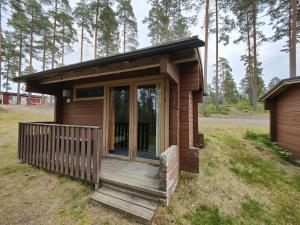 a small wooden cabin with a porch in a field at Ahvenlampi Camping Hostel in Saarijärvi