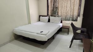 Cama en habitación con escritorio y silla en Hotel Chetan, en Pune 5 fotos más