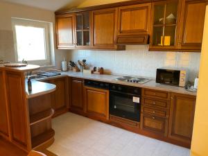 a kitchen with wooden cabinets and a stove top oven at Vila Fjaka in Dugi Rat
