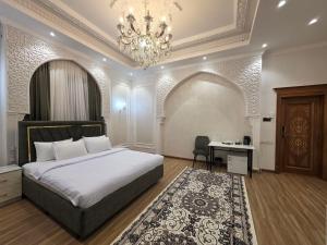 a bedroom with a bed and a chandelier and a desk at Old City Samarkand Hotel in Samarkand