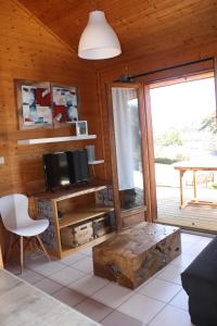a living room with a tv and a wooden wall at Volcans Vacances Les Chalets Du Lac in Aydat