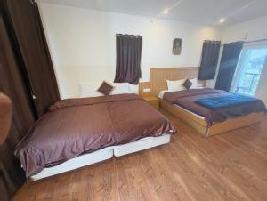 科代卡纳尔Magizham Homestay的两张床在铺有木地板的房间里