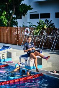 a woman sitting on a bench in a swimming pool at Superpro Samui in Chaweng