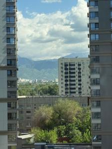 a view of a city from between two buildings at Двухкомнатная квартира с дизайнерским интерьером и видом на горы in Almaty