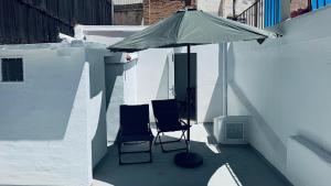 two chairs sitting under an umbrella on a patio at Casa en el centro , con amplia terraza in Vinarós