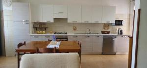 a kitchen with a wooden table and a kitchen with white cabinets at Vittoria in Tortolì
