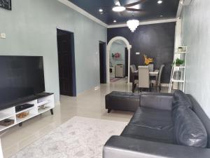 a living room with a black couch and a table at By The River Homestay in Kuala Perlis